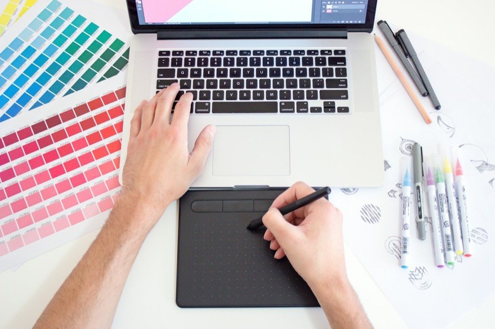 Diseñador gráfico trabajando con tableta digital y muestras de color